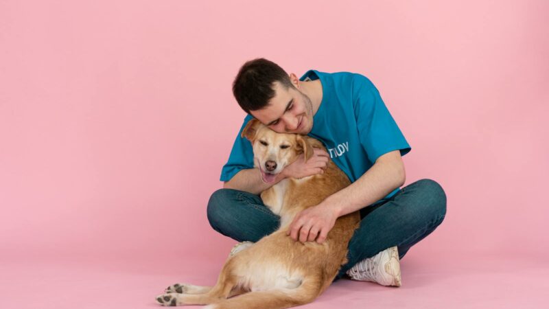 Man Sitting on the Floor while Hugging a Dog